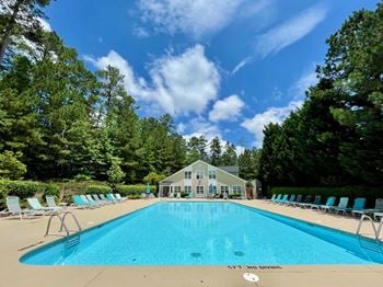 a swimming pool with chaise lounge chairs and a house in the background